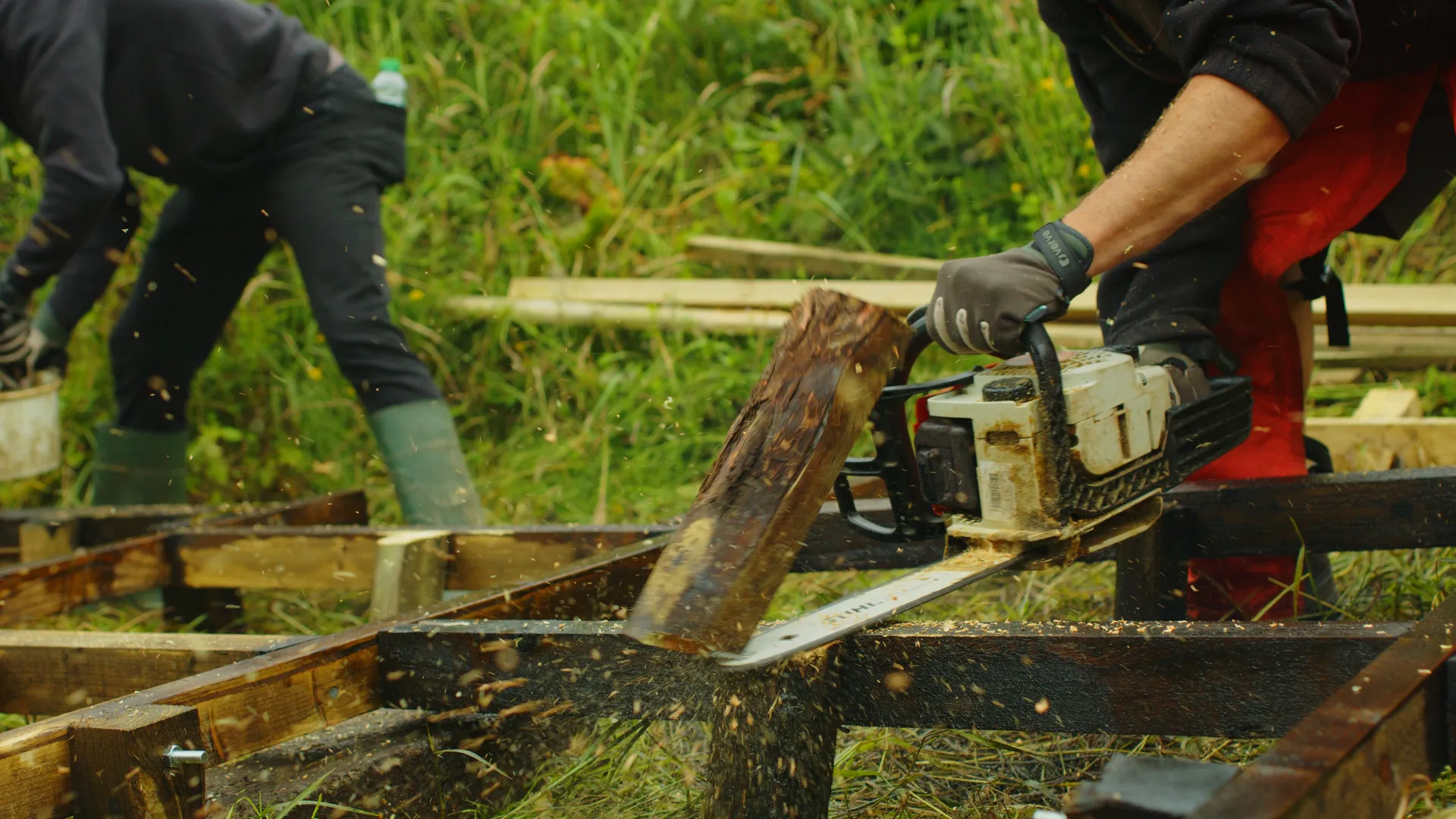 John Ballard using a chainsaw to cut timber during the construction of the bee-safe garden at The Children's Centre, Isle of Man, filmed by DotPerformance for Conister Bank